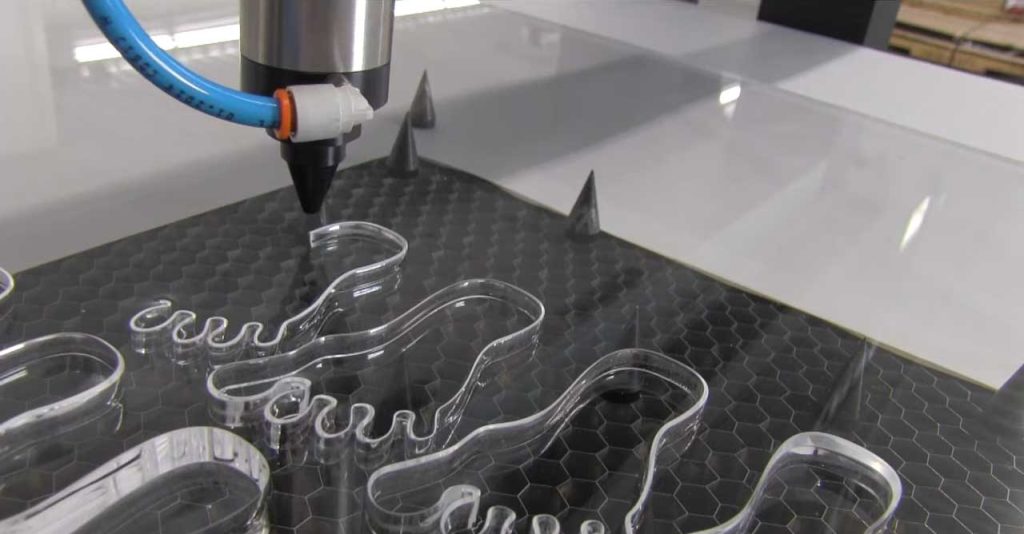 CO2 laser cutter in operation, vector cutting clear acrylic sheet into precise, complex forms.