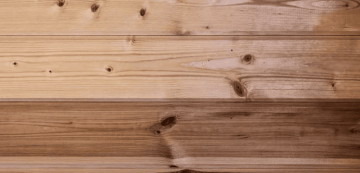 Knotty wood plank demonstrating laser cleaning: a visibly lighter, cleaned section contrasts with the adjacent darker, untreated wood.