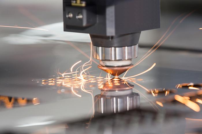 Fiber laser cutting machine head in action, precisely cutting an aluminum sheet and creating bright sparks.